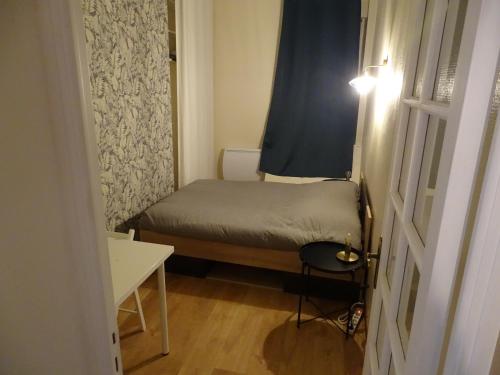 Cette petite chambre comprend un petit lit et une table. dans l'établissement Le Charmant Vannerie, à Dijon