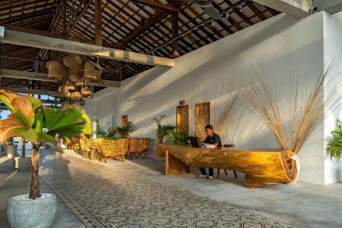 un hombre sentado en un escritorio en una habitación con un ordenador portátil en You&Me Resort en Koh Rong Island