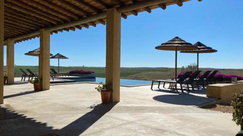 a patio with chairs and umbrellas and a pool at Monte da Aparica in Galeguinha Grande