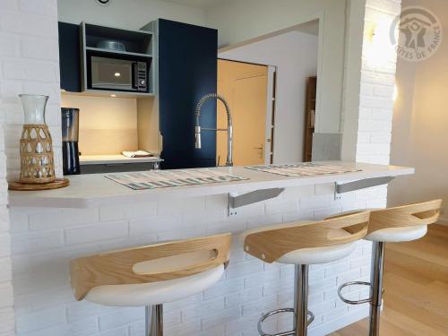 une cuisine avec un comptoir et deux tabourets de bar dans l'établissement Maison à Malo les bains à 5mn de la plage, à Dunkerque