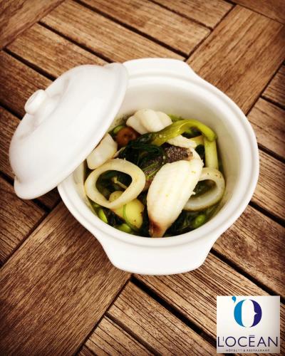 a cup of soup with vegetables and a spoon at Hotel L'Océan in Le Bois-Plage-en-Ré