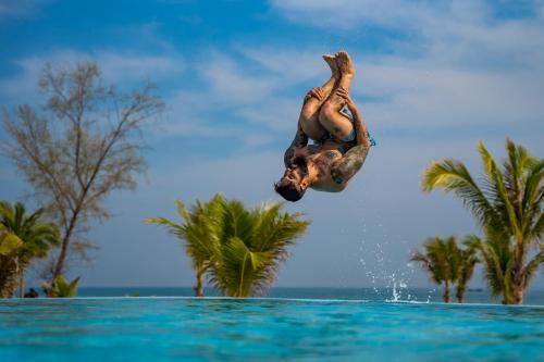 a man jumping into the water from a swimming pool at You&Me Resort in Koh Rong Island