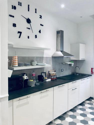 a kitchen with white cabinets and a clock on the wall at Domus Giordano in Rome