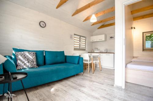 a living room with a blue couch and a kitchen at szumidomek in Mielno