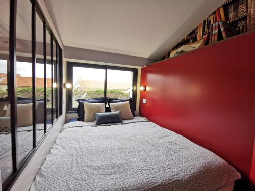 1 dormitorio con 1 cama grande y pared roja en Maisonnette avec terrasse et parking, en Haute-Goulaine