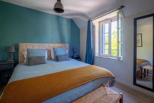 a bedroom with a bed with blue walls and a window at A La Lettre Thé in Molineuf