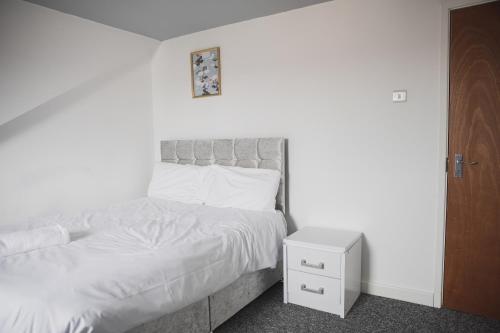 a bedroom with a white bed and a night stand at Leicester House in Leicester