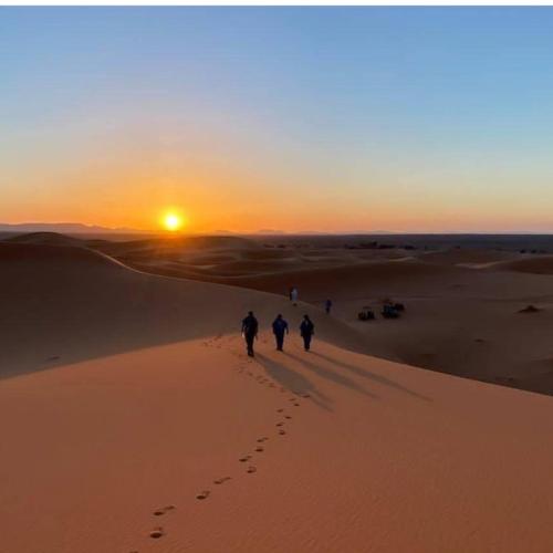 a group of people walking in the desert at sunset at Auberge Sahara Garden in Lac Yasmins