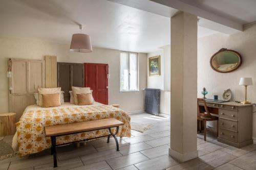 a bedroom with a bed and a table and a desk at A La Lettre Thé in Molineuf