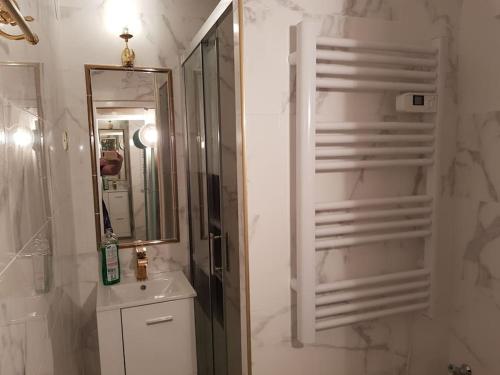 a white bathroom with a sink and a mirror at Clair de plage in Frontignan