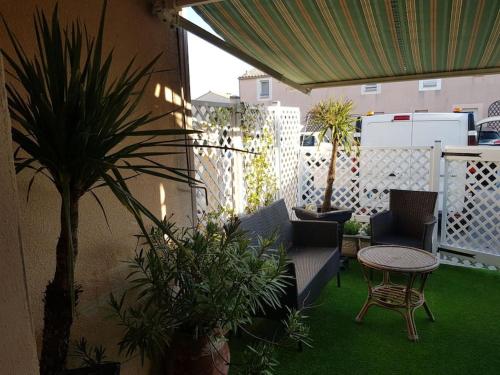a patio with a table and chairs and plants at Clair de plage in Frontignan