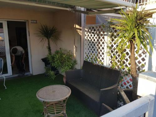 a porch with a bench and a table and plants at Clair de plage in Frontignan