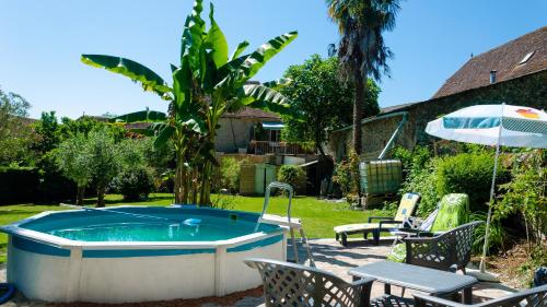 a pool with chairs and an umbrella in a yard at Chez Bouju in Castetnau-Camblong