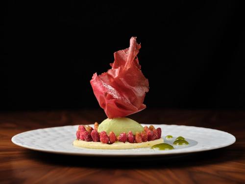 a plate with a piece of bacon on top of a dessert at Hôtel Richer De Belleval - Relais & Châteaux in Montpellier
