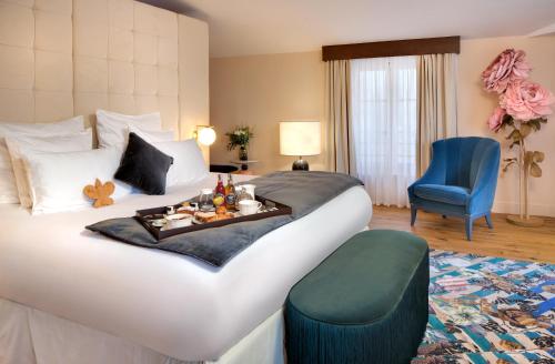 a hotel room with a bed with a tray of food on it at Hôtel Richer De Belleval - Relais & Châteaux in Montpellier