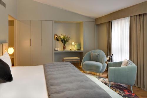 a hotel room with a bed and two chairs at Hôtel Richer De Belleval - Relais & Châteaux in Montpellier