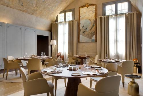 un comedor con mesas, sillas y ventanas en Hôtel Richer De Belleval - Relais & Châteaux en Montpellier