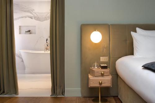 a bedroom with a bed and a bathroom with a tub at Hôtel Richer De Belleval - Relais & Châteaux in Montpellier