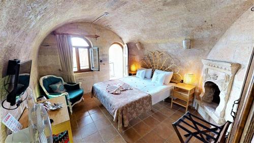 1 dormitorio con 1 cama grande y chimenea en Mimi Cappadocia Luxury Cave Hotel en Uchisar