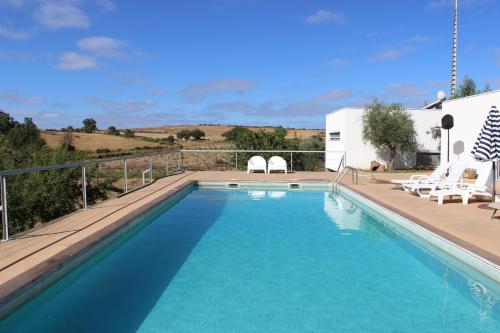 uma piscina com cadeiras e uma casa em Villa Martins em Lagoaça