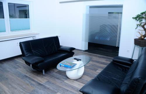 ein Wohnzimmer mit schwarzen Ledermöbeln und einem Tisch in der Unterkunft Bonsai-Ferienwohnung in Bad Laer