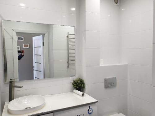 Un baño blanco con lavabo y espejo. en Best Apartment Shevchenka 80, en Leópolis