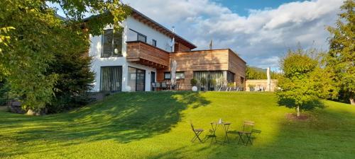 a house on a lawn with chairs and a table at Seeidylle Winkler in Bodensdorf