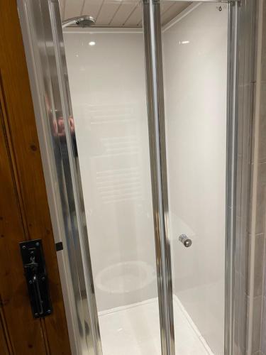 a shower with a glass door in a bathroom at Grapes Hotel, Bar & Restaurant Snowdonia Nr Zip World in Blaenau-Ffestiniog