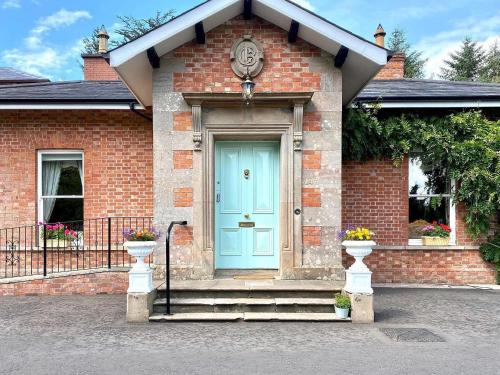 a brick house with a blue door and stairs at Oranmore in Ballymena
