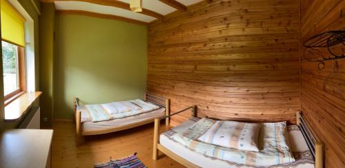 two beds in a room with a wooden wall at Domek wiejski in Dwernik