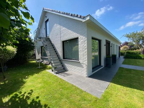 een wit huis met een trap naast een tuin bij B&B 't zwart peird in Poperinge