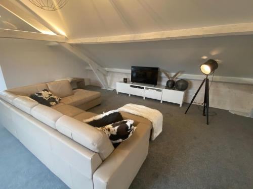 a living room with a white couch and a television at B&B 't zwart peird in Poperinge