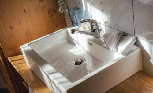 lavabo blanco en el baño con espejo en Guesthouse by the rex, en Zermatt