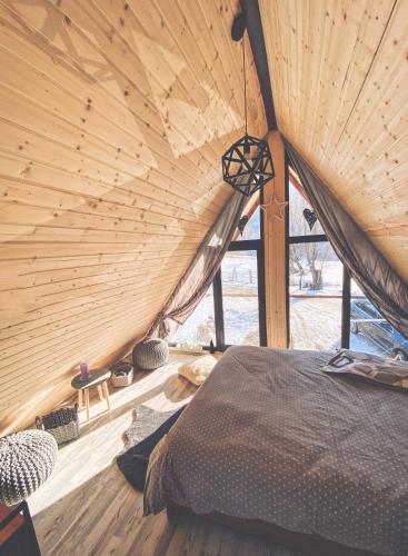 Bett in einem Zimmer mit Holzdecke in der Unterkunft Acasă Straja - Casa Nordică in Lupeni