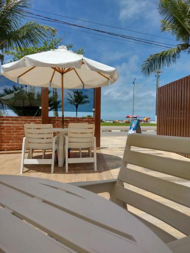 a table and two chairs and an umbrella at Pousada La Naila in Bertioga
