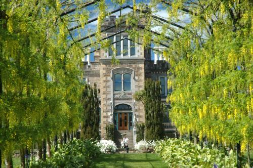 an image of a building through an arcade of trees at Larnach Lodge & Stable Stay in Dunedin