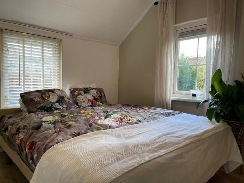 1 dormitorio con 1 cama con colcha de flores y ventana en Royal Veluwe, en Putten