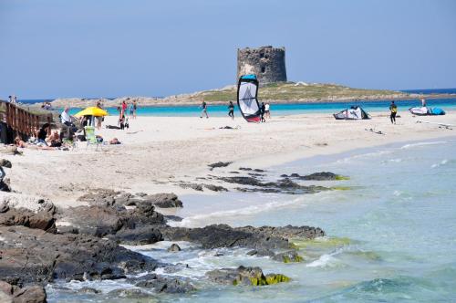 a group of people on a beach near the water at Hotel Geranio Rosso in Stintino