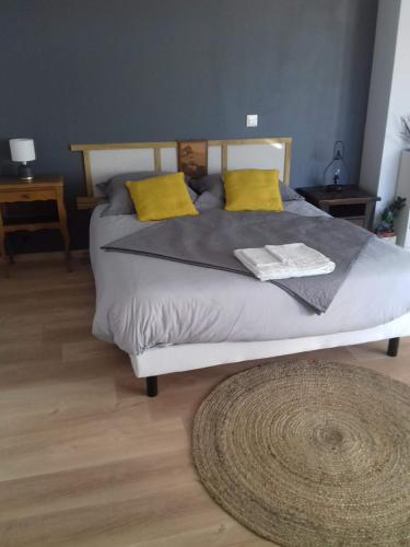 1 dormitorio con 1 cama con almohadas amarillas y alfombra en Agréable chambre meublée, vue sur la vallée de l'Auxois en Villy-en-Auxois