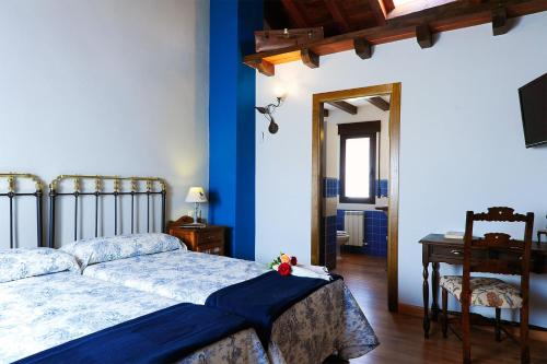 Un dormitorio con una cama con paredes azules y una mesa. en El Valle de la Mantequilla, en Aldehuela del Rincón