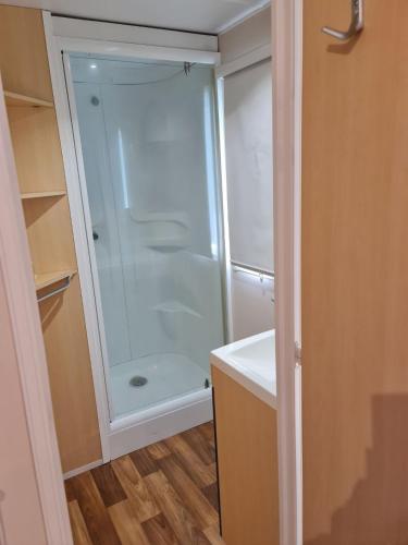 La salle de bains est pourvue d'une douche et d'un lavabo blanc. dans l'établissement MOBIL HOME familiale EN ALSACE11 KM DES GRANDS PARCS, à Boofzheim