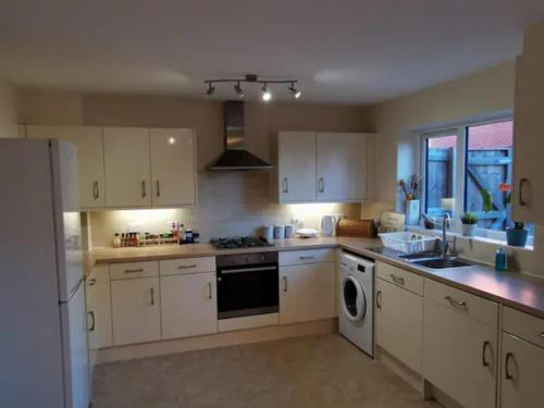 a kitchen with white cabinets and a sink and a dishwasher at Entire 3 bedroom house Manchester free parking in Manchester