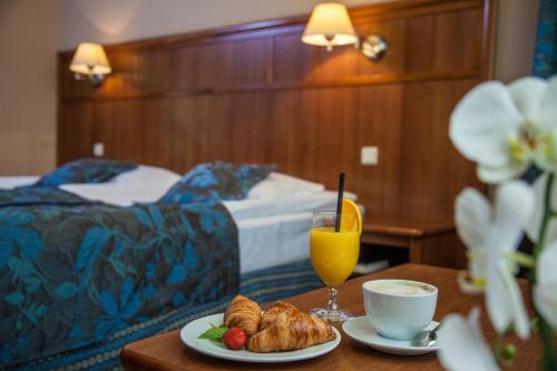 a table with a plate of croissants and a glass of orange juice at Farmona Hotel Business & SPA in Kraków