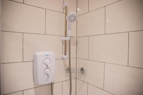 a shower with a shower head on a white tiled wall at Withnell Stays - Apartment Three in Blackpool