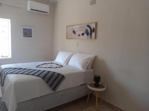 a white bedroom with a bed and a small table at Fabulous Rest Inn in Francistown