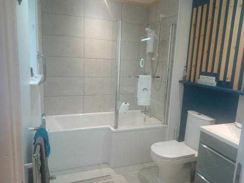 y baño con bañera, aseo y ducha. en Charming lodge cosy comfortable ideal location, en Blairgowrie