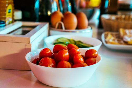 a bowl of tomatoes on a counter with other bowls of peppers at Cinnamon Sally Backpackers Hostel in Rīga