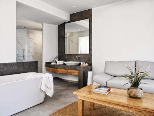ein Badezimmer mit einer Badewanne, einem Waschbecken und einer Couch in der Unterkunft AVATON in Folegandros Chora