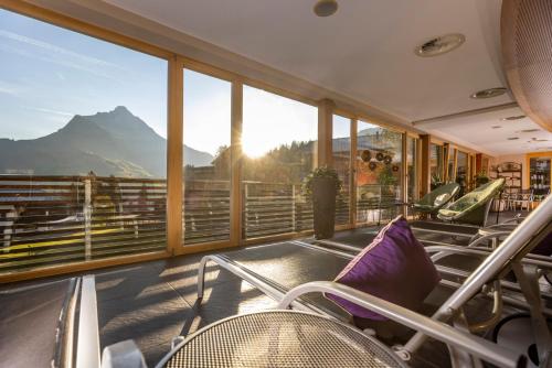 a balcony with chairs and a view of a mountain at Hotel Walserberg in Warth am Arlberg