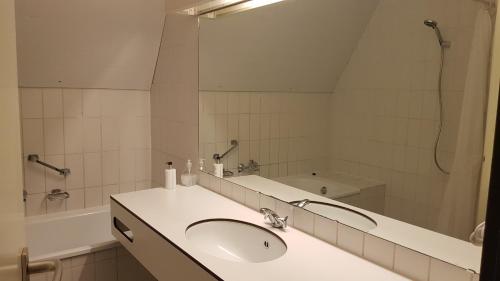 een badkamer met een wastafel, een bad en een spiegel bij City Hotel Winschoten in Winschoten